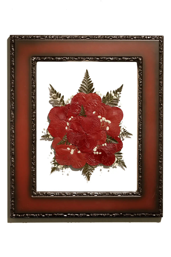 Framed pressed flowers with red roses with gold accents on a white background