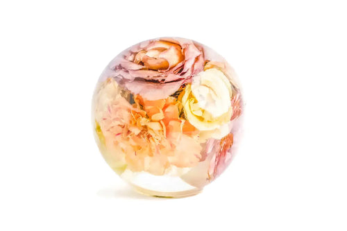 A large resin sphere 6 inch containing a wedding bouquet of carnations and roses.