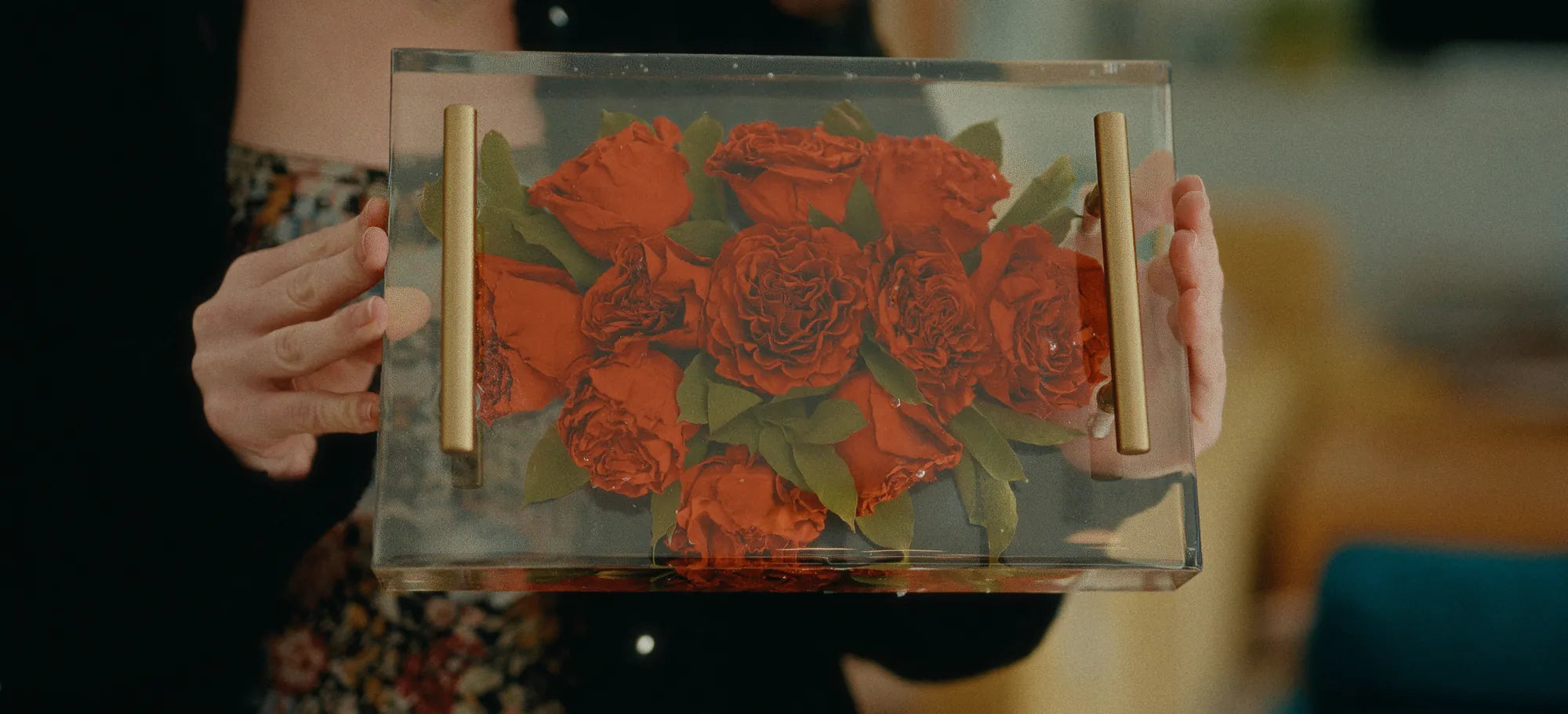 A bouquet of red peonies preserved in a large resin serving tray.