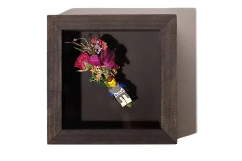 LEGO figure with groom flowers on a boutonniere in a dark stain wooden shadow box.