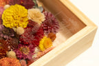 Close-up of a shadow box corner with pressed flowers and clear glass with brand logo