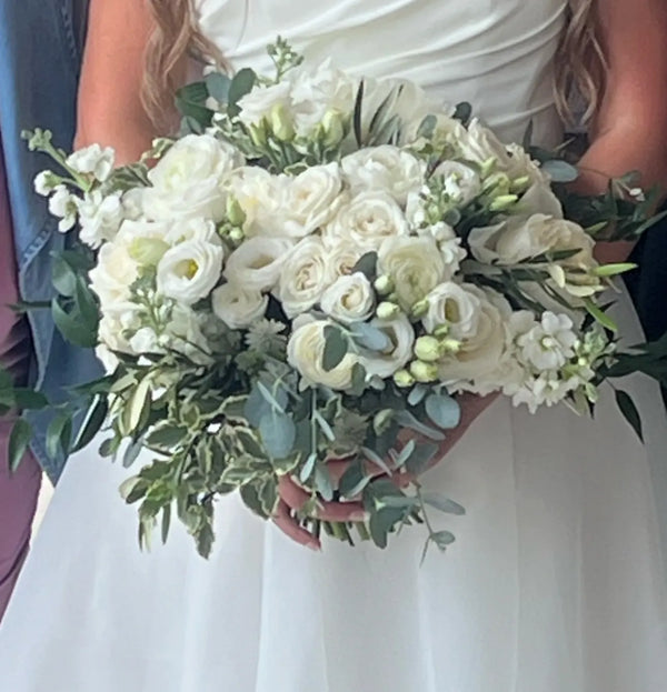 Bouquet of white flowers held by a bride in her white dress
