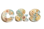Decorative resin letters 'C', '&', and 'S' made of wedding flowers on a white background