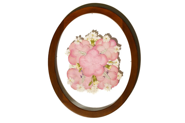Pink wedding flowers preserved in an oval handmade brown frame with a clear background