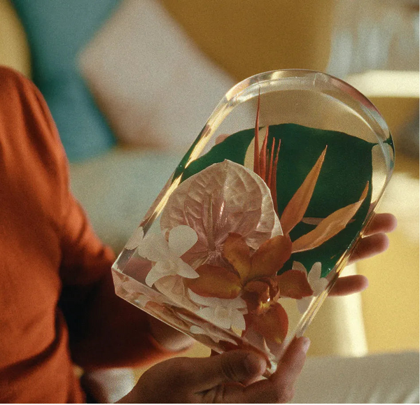 Person holding a decorative resin preservation with floral design in a casual setting