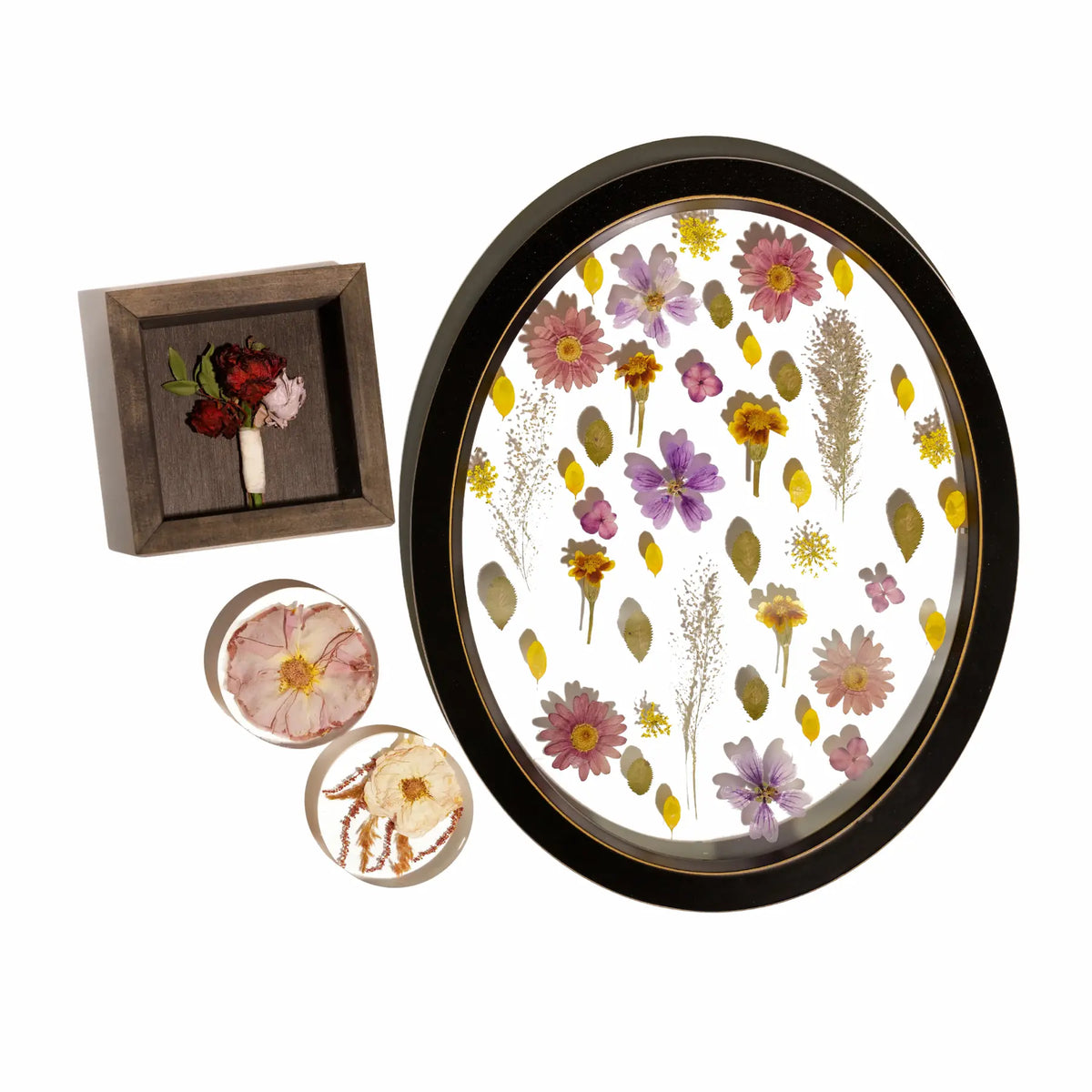 One pressed flower frame with floating display of flowers, a boutonniere shadow box with red roses, and two resin flower coasters.