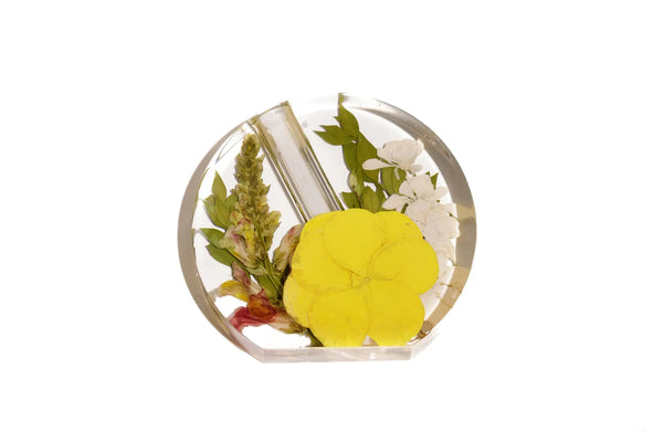 A small flat bottomed round resin propagator vase made of preserved wedding flowers.