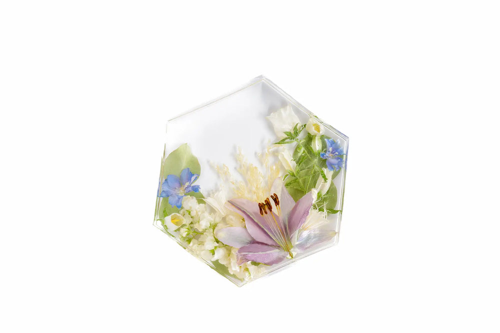 Hexagonal resin block with pressed flowers on a white background