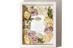 Preserved flower arrangement in a decorative shadow box featuring a wedding invite