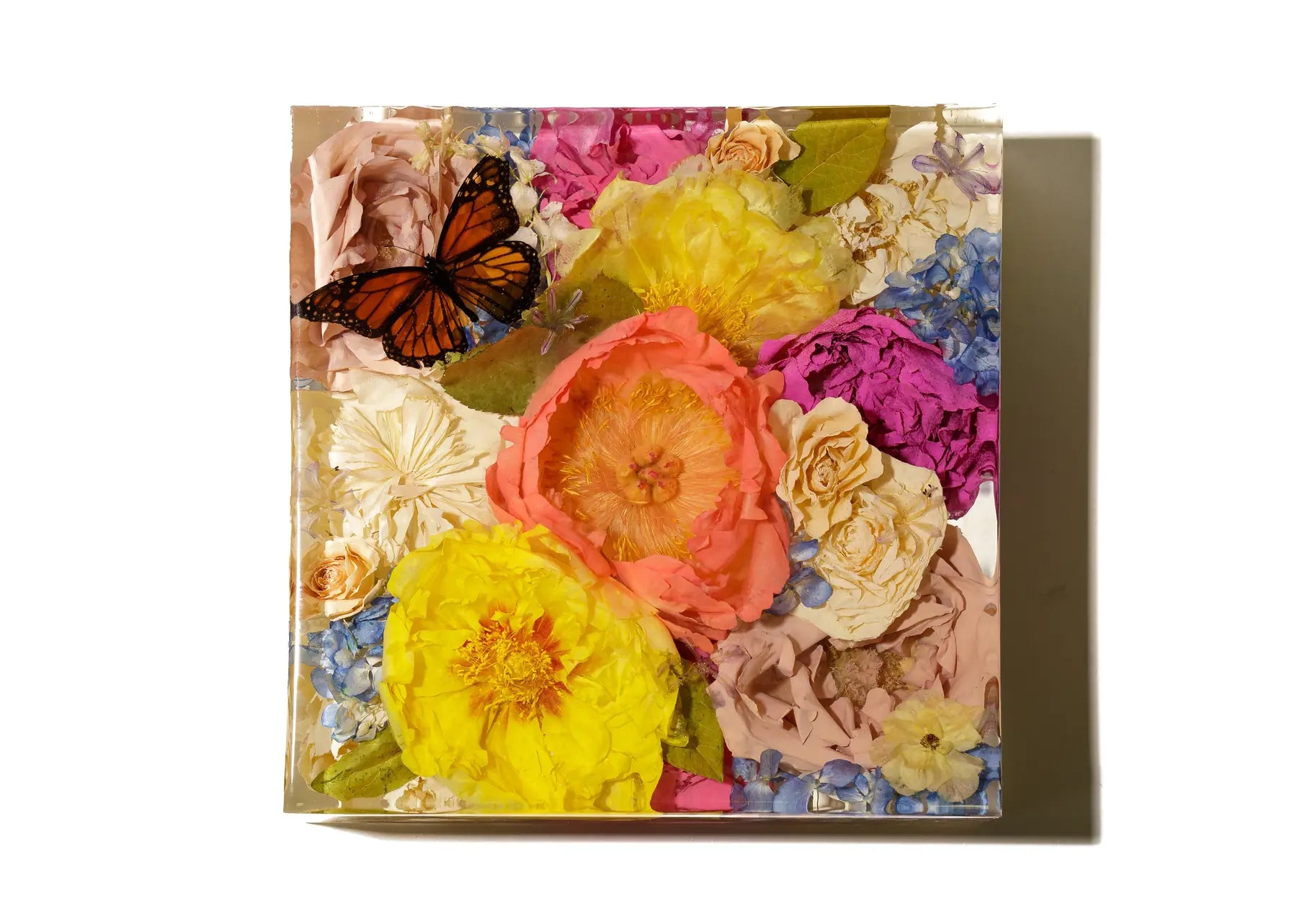 A large square bouquet block 10 inch in size featuring multi colored peonies and carnations and a butterfly preserved in resin.