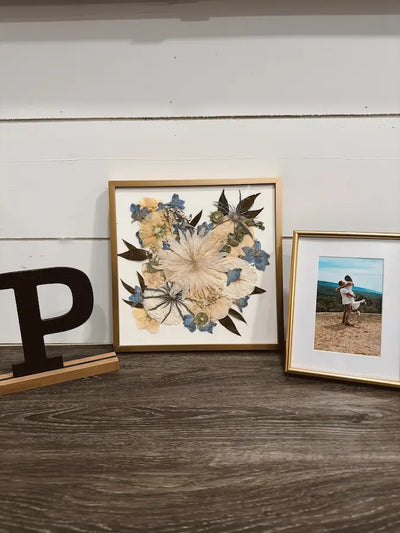 Pressed wedding bouquet in square frame with white background near wedding photo