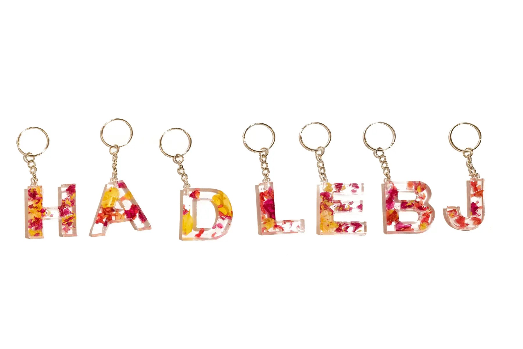 Preserved flower keychains featuring the letters 'H' , 'A' , 'D', 'L', 'E', 'B', and 'J' with silver keychains