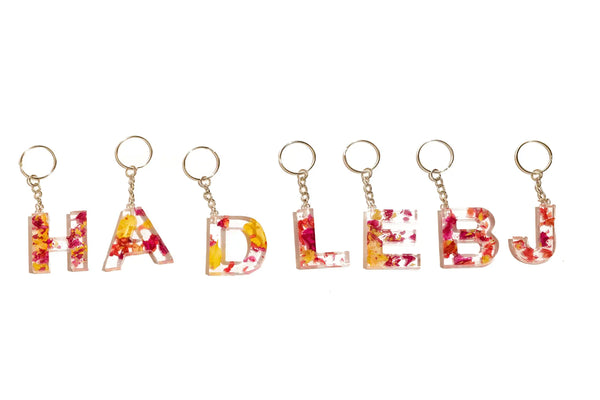 Preserved flower keychains featuring the letters 'H' , 'A' , 'D', 'L', 'E', 'B', and 'J' with silver keychains