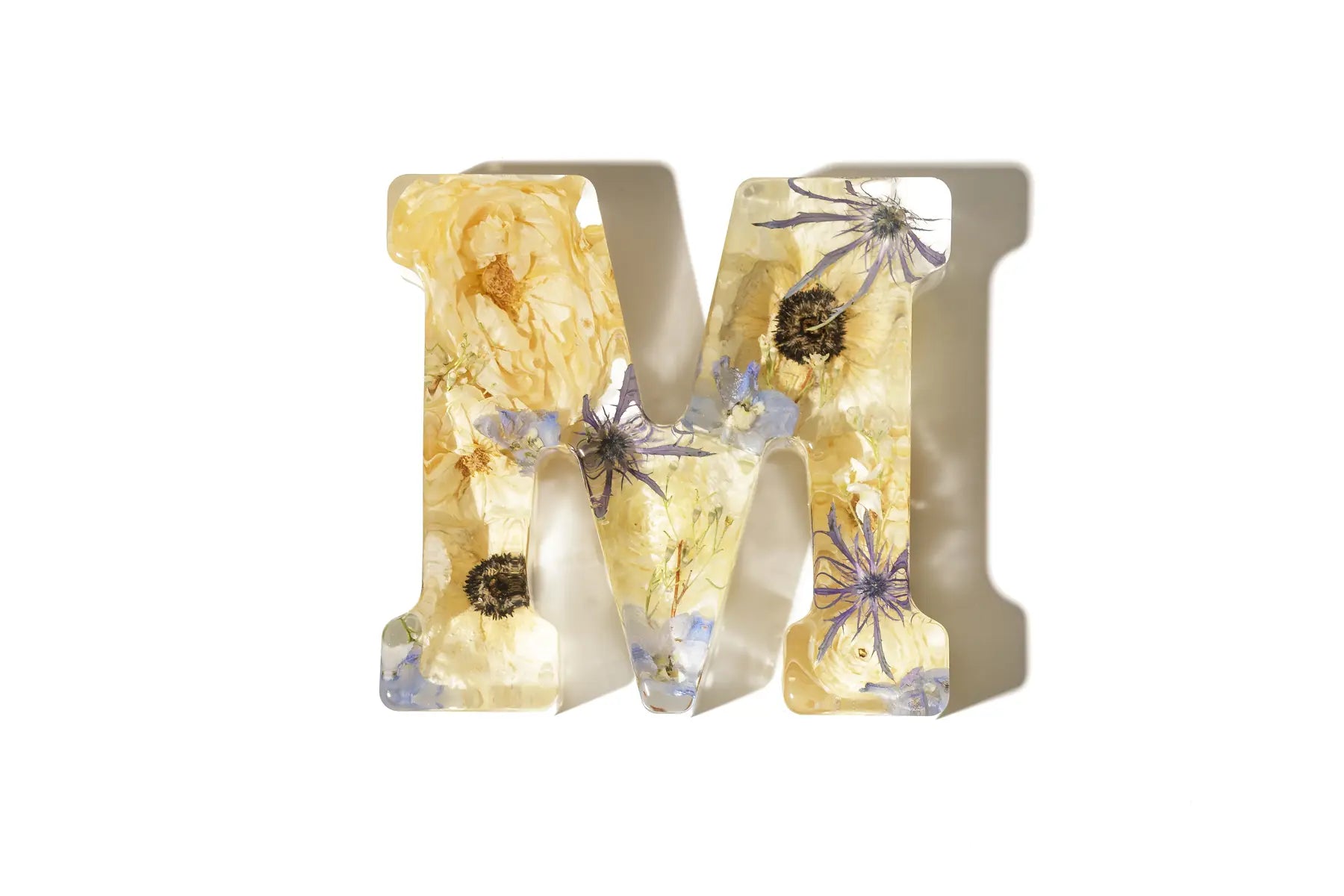 Large resin decorative letter 'M' with light colored wedding flowers