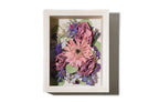 Preserved floral arrangement framed in a white wooden shadow box on a white background