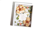 Rose floral arrangement in a white shadowbox with a card inside on a white background