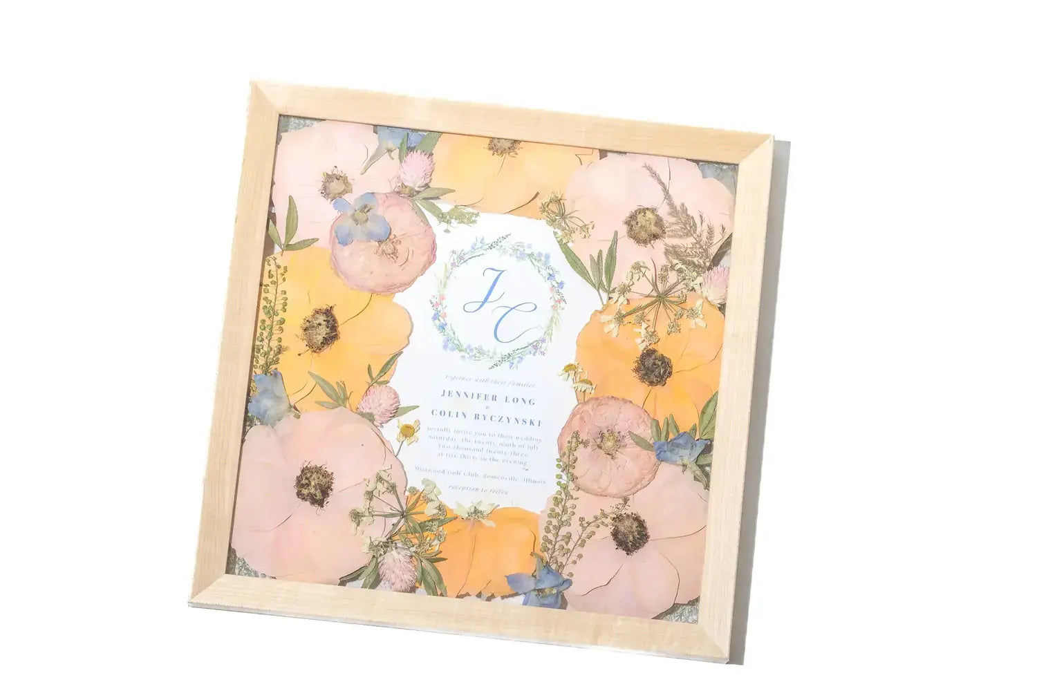 11x11 square pressed flower frame with wedding bouquet and a wedding invitation center oriented 