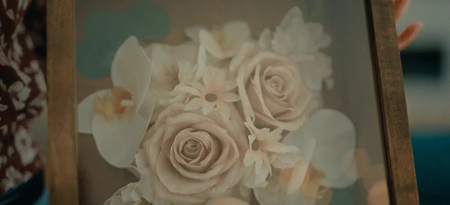 Close-up of white roses and orchids in a stained brown handmade wood shadow box